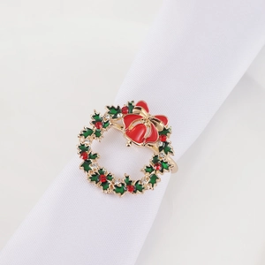 Close-up of Christmas wreath napkin ring with red bow and rhinestones on white cloth