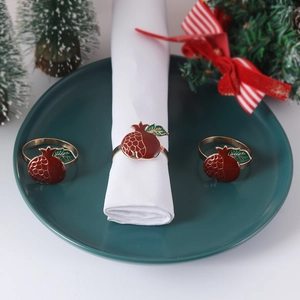 Goldene Granatapfel-Serviettenringe mit roter Emaille auf grünem Teller für die Festtafel