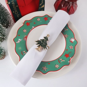 Close-up of green enamel Christmas tree napkin ring with gold star on a festive plate