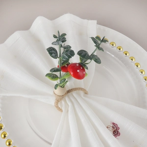 Forest style napkin ring with red mushroom and green leaves on white linen napkin