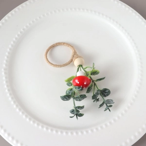 Rustic napkin ring with red mushroom and green leaves on a white ceramic plate