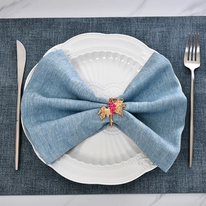 Grape napkin ring in gold alloy with pink beads on a blue napkin for dining decor