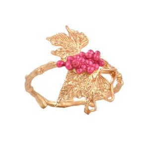 Artistic grape napkin ring with golden leaf design and pink fruit on a white background