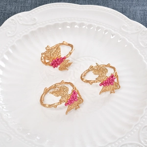 Grape vine napkin rings in gold zinc alloy with purple beads set of 3 on white plate
