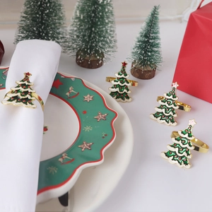 Close-up of golden Christmas tree napkin rings with green enamel and red star details