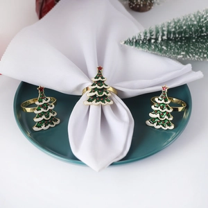 Detailed view of three gold Christmas tree napkin rings with green and white enamel finish