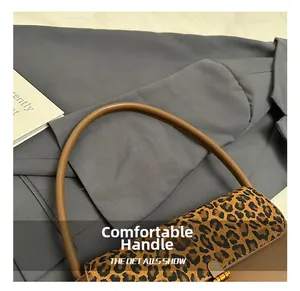 Detail of leopard print handbag with ergonomic brown leather handle and gold buckle