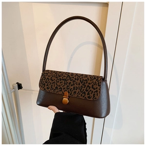 Detail of leopard print flap and gold clasp closure on a dark brown baguette bag