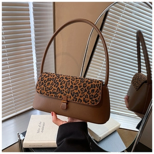 Detail of leopard print baguette bag with leather strap and metal buckle in soft lighting