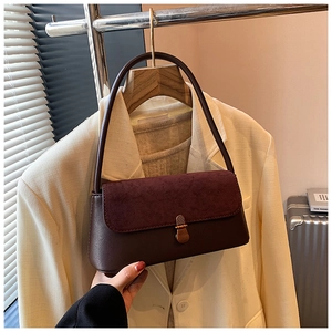 Detail of vintage burgundy shoulder bag showing suede patchwork and metal clasp on flap