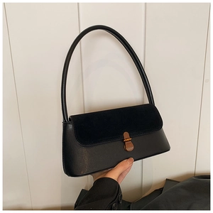 Détail du sac baguette noir avec rabat en daim et fermoir en bronze vintage