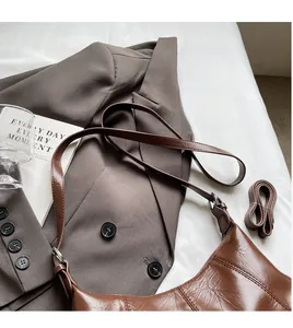 Detail of vintage brown glossy leather shoulder bag with adjustable long straps