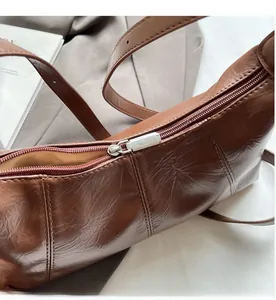 Detail of silver metal zipper and vintage oil wax leather texture on brown crossbody bag