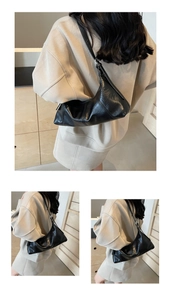 Detail of black crescent shoulder bag with vintage pleated texture and silver hardware