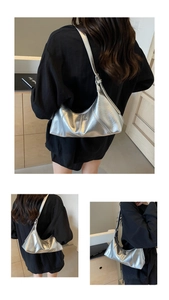 Detail of silver crescent shoulder bag featuring metallic wrinkled texture and sleek design