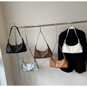 Five crescent cross-body bags in vintage oil wax leather hanging on a metal studio rack