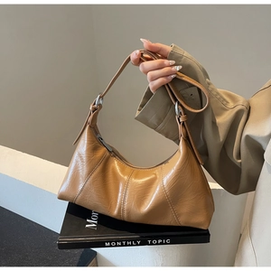 Detail of vintage brown oil wax leather hobo bag with pleated texture on black books