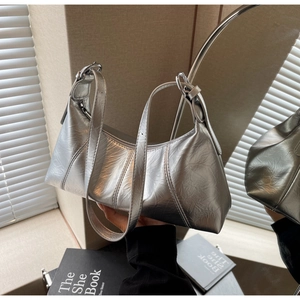 Detail of silver crescent bag featuring metallic crinkled texture and sleek shoulder strap