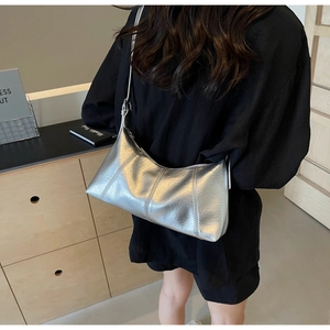 Detailed view of silver metallic crescent bag with wrinkled texture on female shoulder