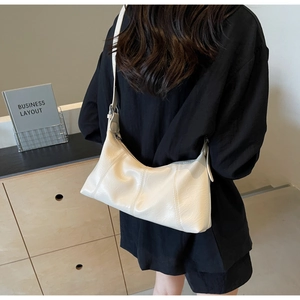 Detailed view of cream pleated faux leather shoulder bag with adjustable silver buckle