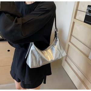 Silver pleated hobo bag with black strap shown from a stylish side view on shoulder