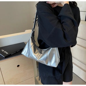 Detail showing metallic silver crescent shoulder bag with stitch texture and strap