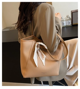 Detail of tan lychee grain leather tote bag with elegant silk scarf on the handle