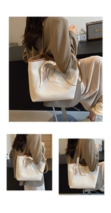 Detail of lychee pattern leather tote bag with silk scarf handle and gold lettering