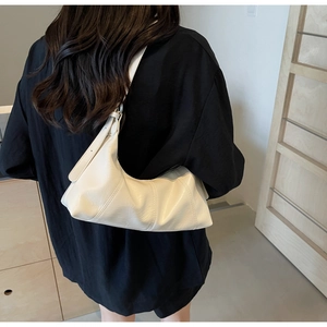 Model wearing a vintage-style creamy white leather hobo bag with stitched details
