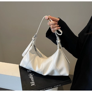 Close-up of white pleated crescent bag with glossy texture and silver metal hardware detail