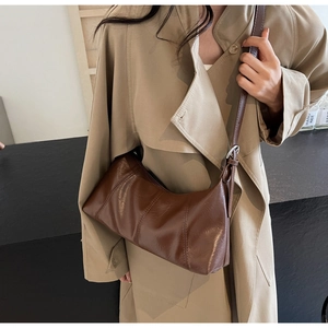 Detail of vintage brown leather crescent bag with vertical stitching and adjustable strap