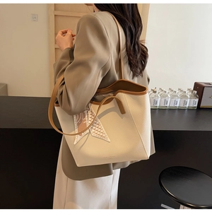 Detail of off-white tote bag with lychee texture, brown straps, and a silk scarf accent