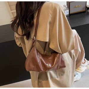 Brown oil wax leather crescent bag shown on model with decorative radial stitching