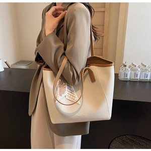 Detail of cream lychee leather tote bag with brown straps and decorative scarf accessory