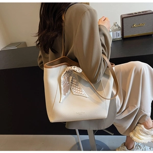 Chic cream leather tote bag with brown straps and silk scarf detail shown on shoulder