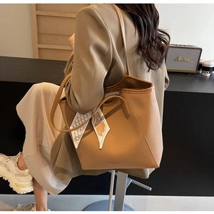 Brown leather tote bag detail with geometric printed scarf on handle and double straps