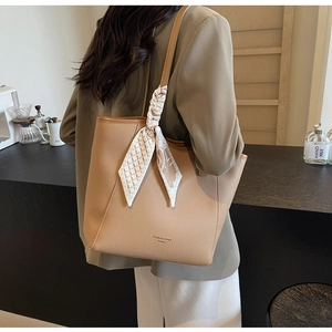 Detail of khaki pebbled leather tote bag with printed silk scarf on the handle