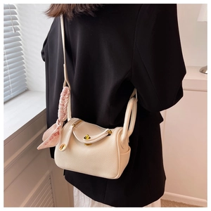 Détail du sac en cuir grainé blanc cassé avec fermoir doré et foulard en soie décoratif