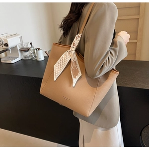 Detailed view of camel leather tote with decorative scarf handle and textured finish
