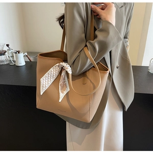 Close-up of khaki lychee grain tote bag with decorative silk scarf on handle