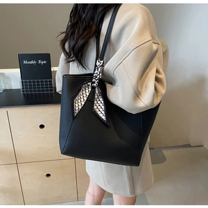 Detailed side view of a black pebble leather tote bag with a decorative silk scarf