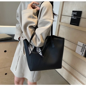 Close-up of black pebble leather tote bag with a geometric silk scarf on the handle
