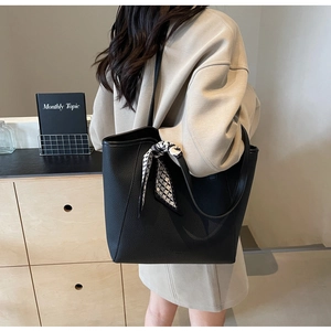 Detail of black pebbled leather tote bag with a geometric pattern scarf on the handle