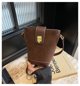 Detail of vintage brown bucket bag showing suede texture and golden metal lock
