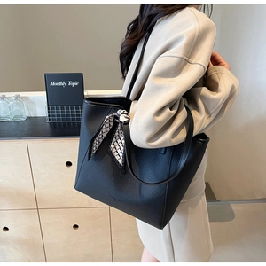 Close-up of black lychee texture leather tote bag with geometric silk scarf detail