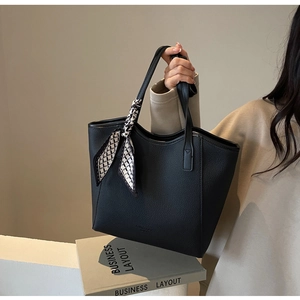 Detail of black pebbled leather tote bag with decorative black and white patterned scarf