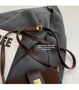 Detail of adjustable leather strap and gold buckle on a brown suede bucket bag