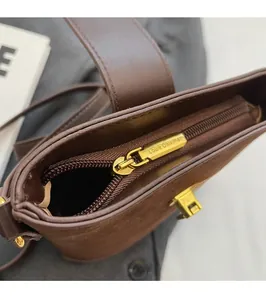 Detailed shot of smooth golden metal zipper and brown leather texture on a bucket bag