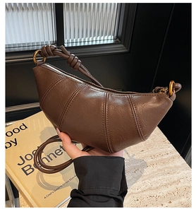 Gros plan sur le sac croissant en cuir marron foncé avec lignes matelassées et anneau chic