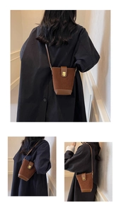 Detail of caramel brown bucket bag in suede and leather with gold metal buckle